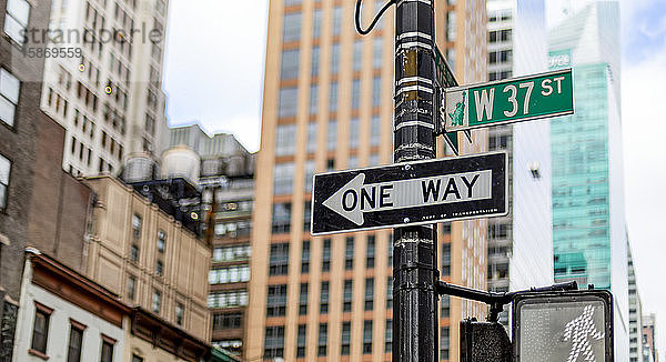 Straßenschilder an einem Pfosten  eine Einbahnstraße  Fußgängersignal und West 37th Street  Manhattan; New York City  New York  Vereinigte Staaten von Amerika