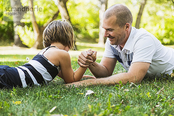 Ein Vater ringt mit seiner kleinen Tochter in einem Park Armdrücken; Edmonton  Alberta  Kanada