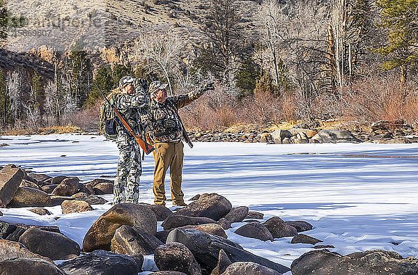 Jäger mit Tarnkleidung und Gewehr  die mit einem Fernglas hinausschauen; Denver  Colorado  Vereinigte Staaten von Amerika