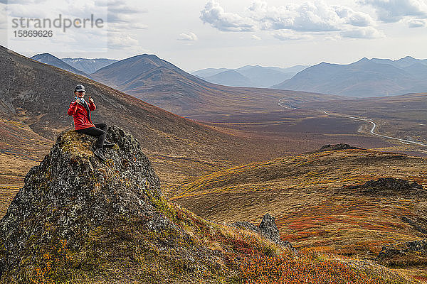 Frau bei der Erkundung der Berge entlang des Dempster Highway im Herbst; Yukon  Kanada