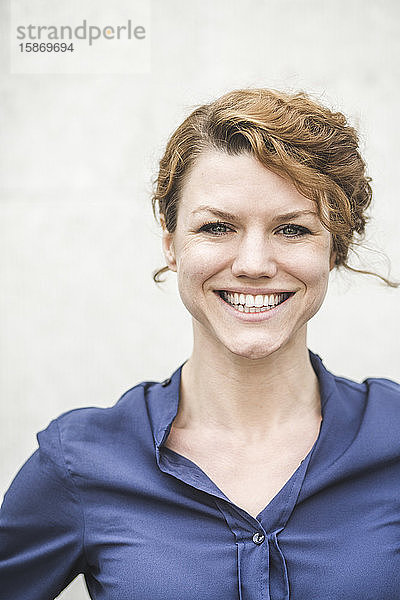 Porträt einer lächelnden Unternehmerin  die an der Wand steht