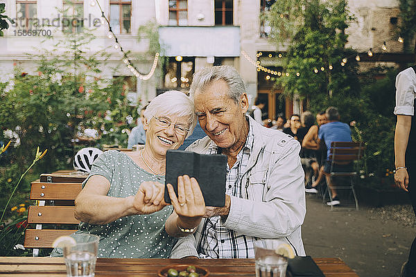 Lächelnde Frau  die sich mit einem älteren Mann im Restaurant in der Stadt vergnügt