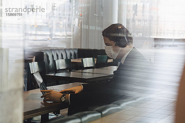 Mann mit Gesichtsmaske bei der Arbeit im Café