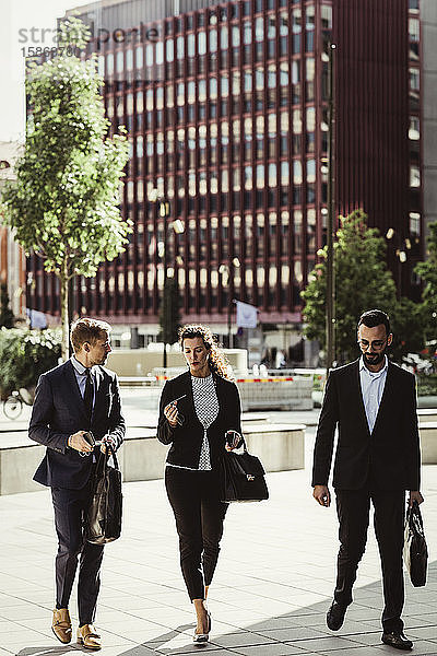Unternehmer bespricht Strategie mit männlichen und weiblichen Kollegen beim Spaziergang im Freien
