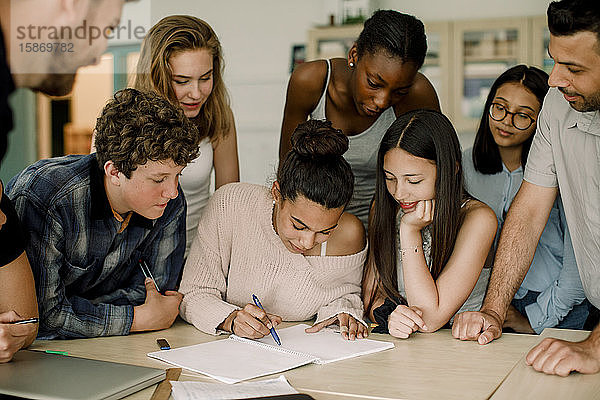 Frau studiert mit Freunden  während der Professor im Klassenzimmer assistiert