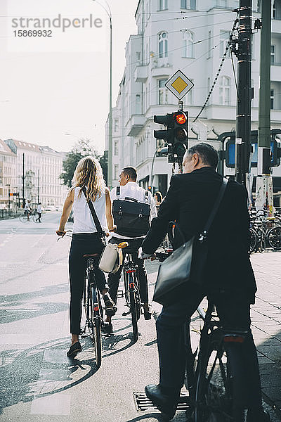 Geschäftskollegen in voller Länge mit dem Fahrrad auf der Straße in der Stadt