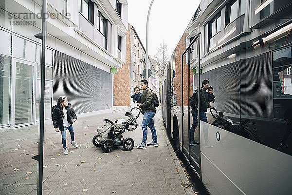 Vater hält Sohn mit Tochter auf Fußweg gegen Bus in der Stadt