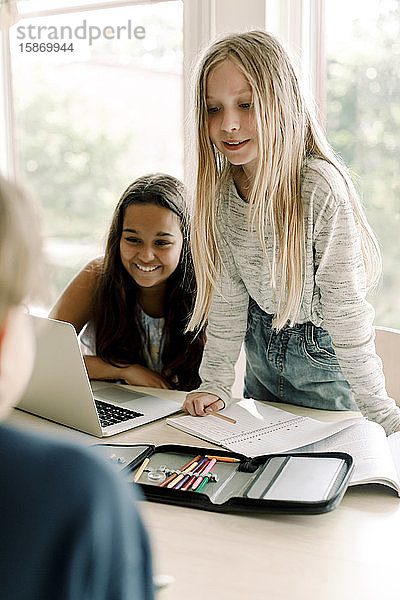 Studentin schaut  während sie einem Freund im Klassenzimmer zur Seite steht