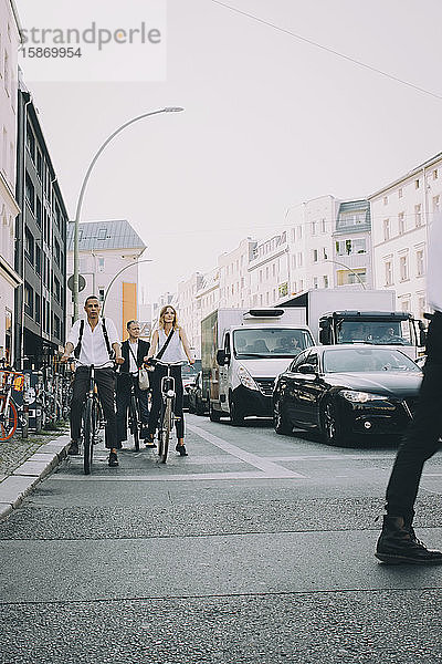 Vollständige Länge der männlichen und weiblichen Mitarbeiter  die in der Stadt auf der Straße Fahrrad fahren