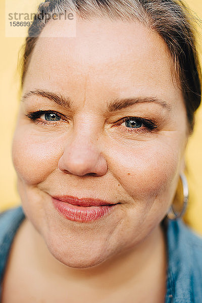 Nahaufnahme-Porträt einer lächelnden Frau vor gelbem Hintergrund