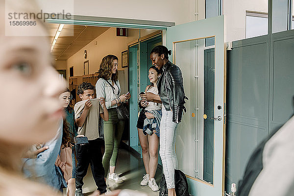 Lächelnde Junior-High-Schüler stehen an der Tür im Schulkorridor