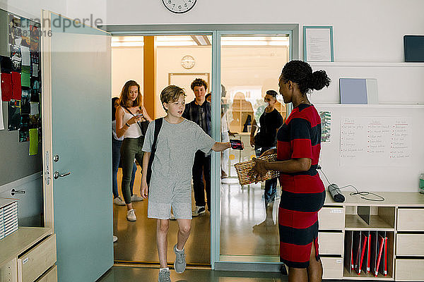 Studentin gibt einer Professorin ein Telefon  während sie im Klassenzimmer geht