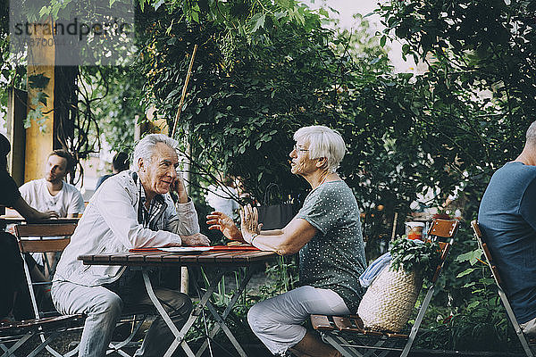 Ältere Frau unterhält sich mit Mann  während sie in einem Restaurant in der Stadt sitzt
