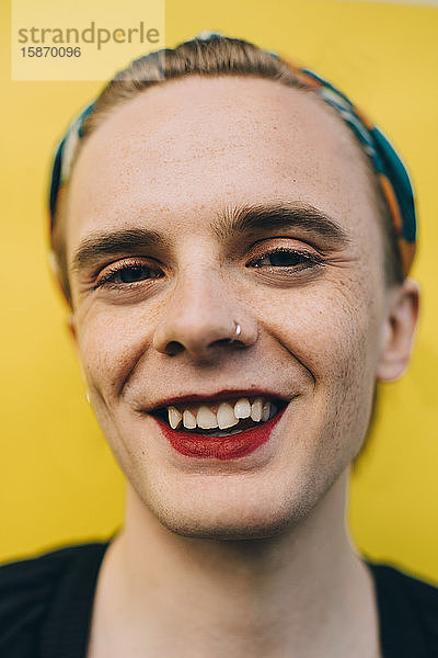 Porträt eines glücklichen  selbstbewussten jungen Mannes vor gelbem Hintergrund