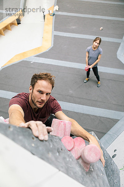 Hochwinkelporträt eines Mannes  der in einer Turnhalle Felsklettern übt