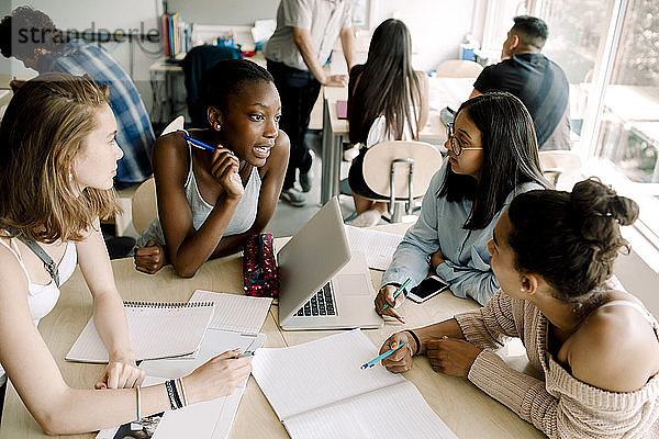 Mädchen im Teenageralter diskutieren am Tisch im Klassenzimmer