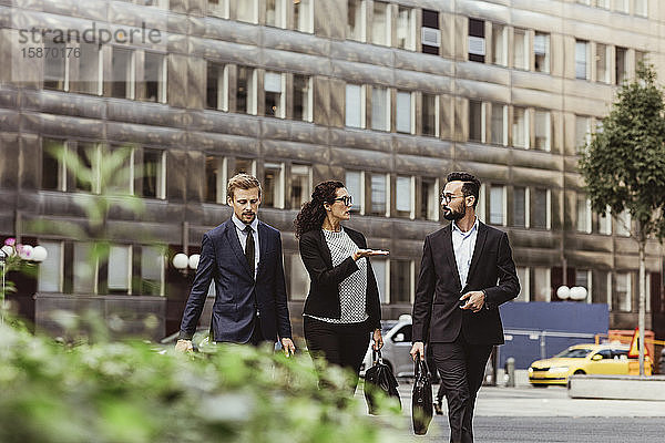 Unternehmerin bespricht Geschäftsstrategie mit männlichen Kollegen beim Spaziergang im Freien