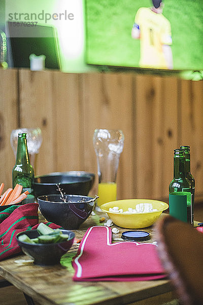 Snacks und Getränke auf dem Tisch gegen den Fernseher im Wohnzimmer