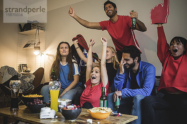 Multiethnische Freunde schauen Sport  während sie zu Hause auf dem Sofa sitzen