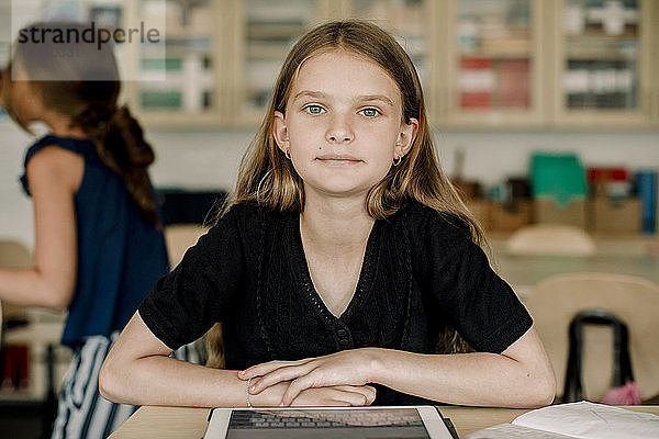 Porträt einer Schülerin mit digitalem Tablett im Klassenzimmer sitzend