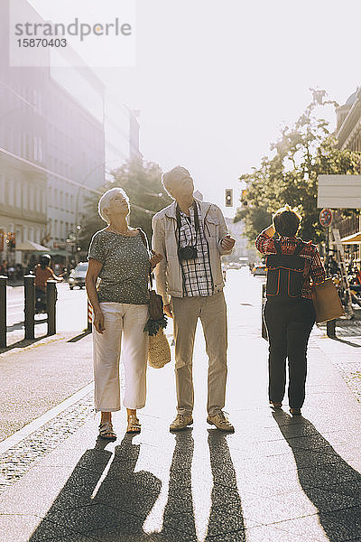 Älteres Ehepaar in voller Länge schaut auf  während es auf dem Bürgersteig in der Stadt steht