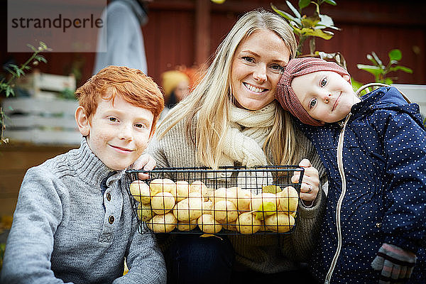 Porträt einer Mutter mit Kartoffelkorb von Kindern im Hof sitzend