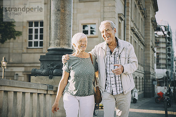 Lächelnder Arm eines älteren Mannes  der an einem sonnigen Tag mit einer Frau in der Stadt spazieren geht