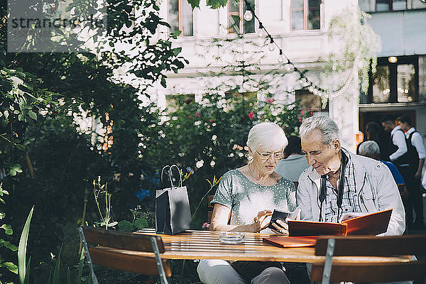 Ältere Frau benutzt Mobiltelefon  während sie mit ihrem Partner im Restaurant in der Stadt sitzt