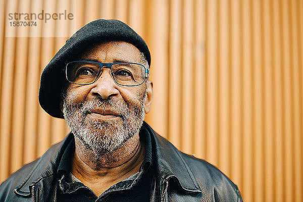 Lächelnder älterer Mann mit Brille an der Wand