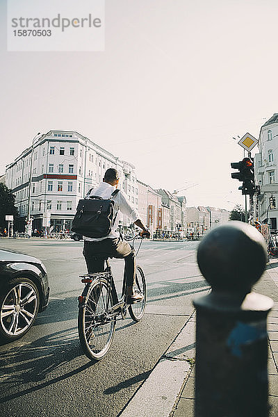 Rückansicht eines Geschäftsführers mit dem Fahrrad auf der Straße in der Stadt gegen den Himmel