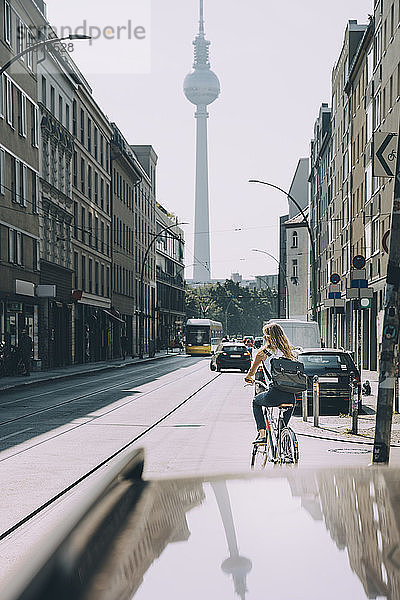 Rückansicht einer Geschäftsfrau  die auf der Straße in der Stadt Fahrrad fährt