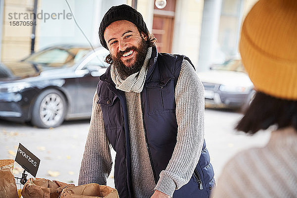 Lächelnder Mann schaut weiblichen Verkäufer an  während er am Marktstand steht