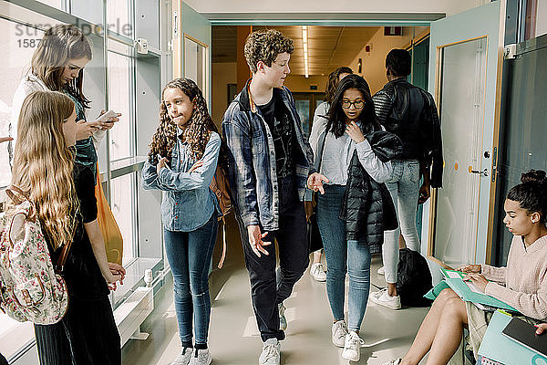 Männliche und weibliche Schüler in der Mittagspause im Schulkorridor