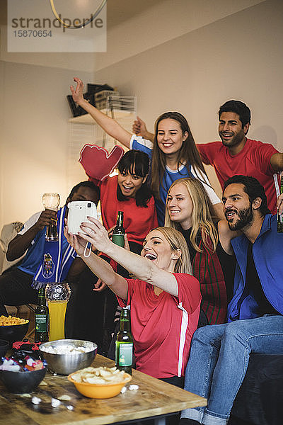 Fröhliche Freunde  die sich mit der Sofortbildkamera beim Sport zu Hause fotografieren