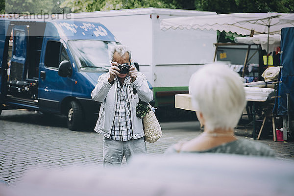Senior-Tourist fotografiert Frau im Stehen in der Stadt