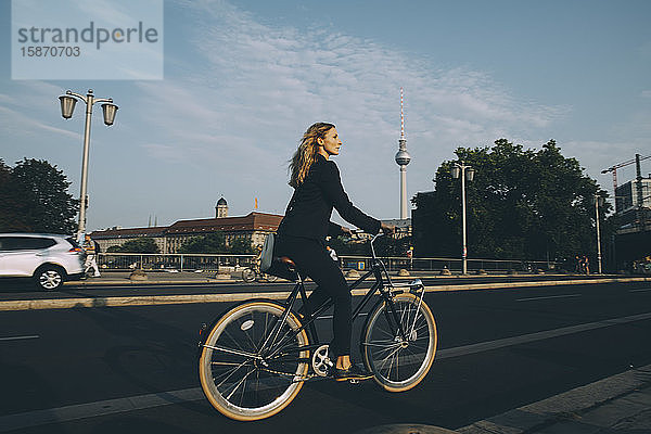 Seitenansicht einer Geschäftsfrau  die auf der Straße in der Stadt Fahrrad fährt
