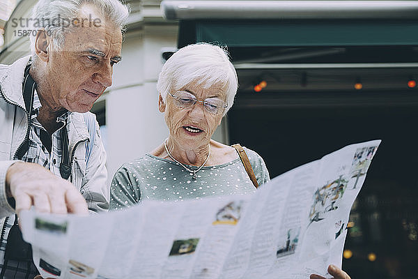 Ältere Frau liest Karte  während sie im Urlaub mit ihrem Partner in der Stadt steht