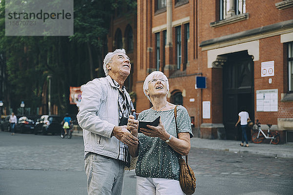 Ältere Männer und Frauen schauen auf  während sie in der Stadt auf der Straße stehen