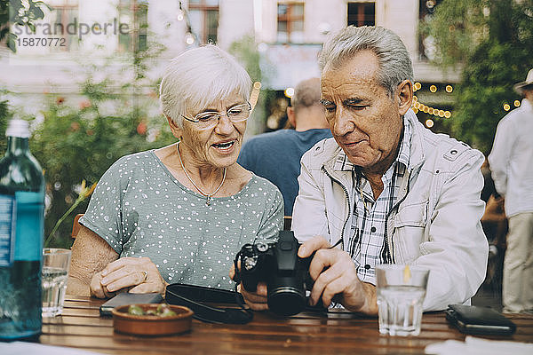 Älterer Mann zeigt Frau Kamera  während er in einem Restaurant in der Stadt sitzt
