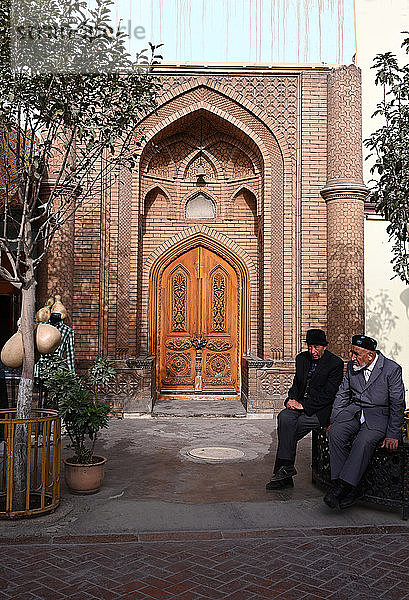 Zwei uigurische Muslime sitzen vor einer Moschee im Stadtzentrum  Kashgar  Xinjiang  China  Asien