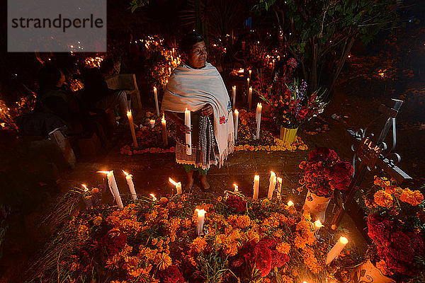 Zapotekische Frau mit Kerze zwischen mit Ringelblumen geschmückten Gräbern  Atzompa  Oaxaca  Mexiko  Nordamerika