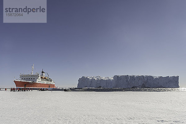 Großer Eisberg und Expeditionsschiff gegen Meereis  Antarktis  Polarregionen
