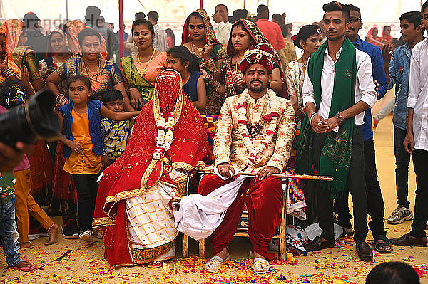 Braut und Bräutigam mit Gästen bei ihrer Hochzeit im Rahmen einer Mehrfachhochzeit im Zelt  Bhuj  Gujarat  Indien  Asien