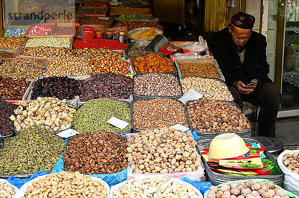 Uigurisch-muslimischer Markthändler  der lokal angebaute und getrocknete Früchte und Nüsse verkauft  Kashgar  Xinjiang  China  Asien