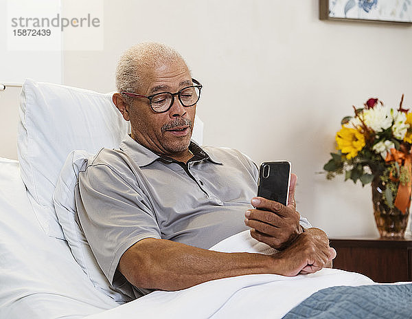 Älterer Mann benutzt Smartphone im Bett