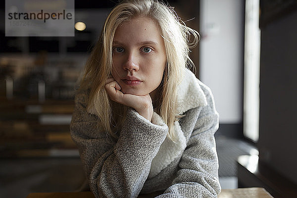 Junge Frau mit Wollmantel im Cafe