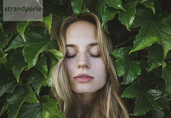 Frau mit geschlossenen Augen inmitten von Blättern