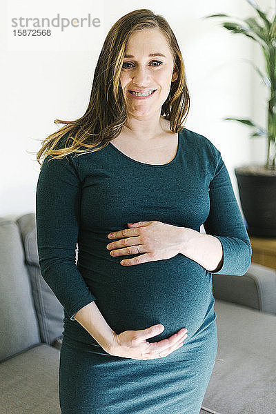 Porträt einer schwangeren Frau  die ihren Bauch berührt