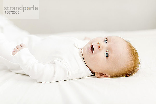 Porträt eines kleinen Jungen (2-3 Monate) auf dem Bett liegend