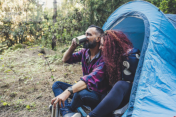 Lächelndes Paar trinkt am Zelt